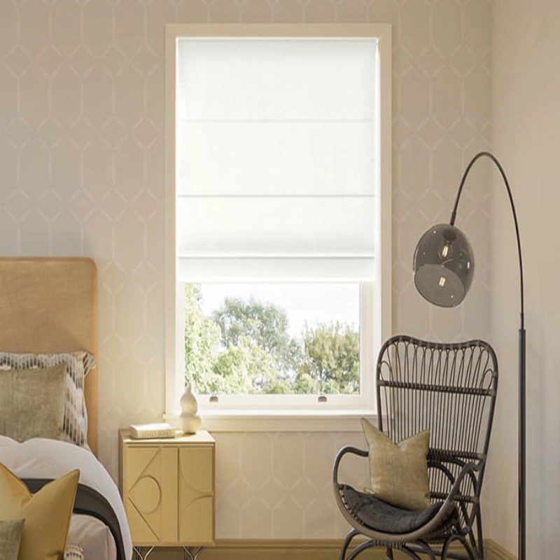 Modern bedroom with a patterned wallpaper, a bed, a chair, and a window covered with white Roman shades