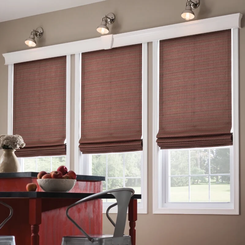 a kitchen with three windows covered with Roman shades. The shades are a dark brown color with a subtle pattern