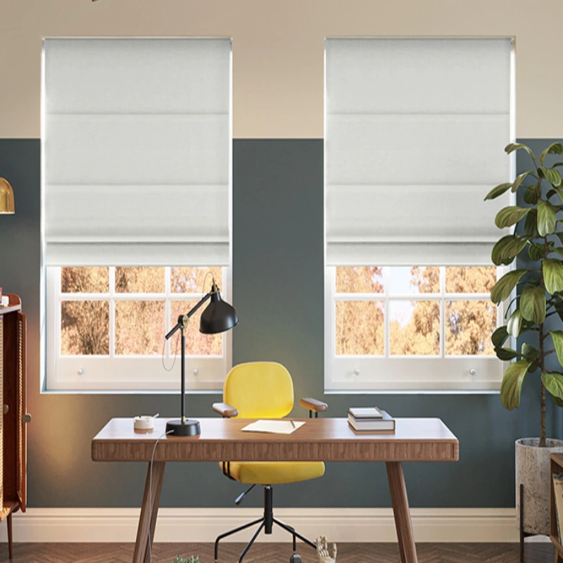 office with a desk, chair, and two windows covered with white Roman shades.