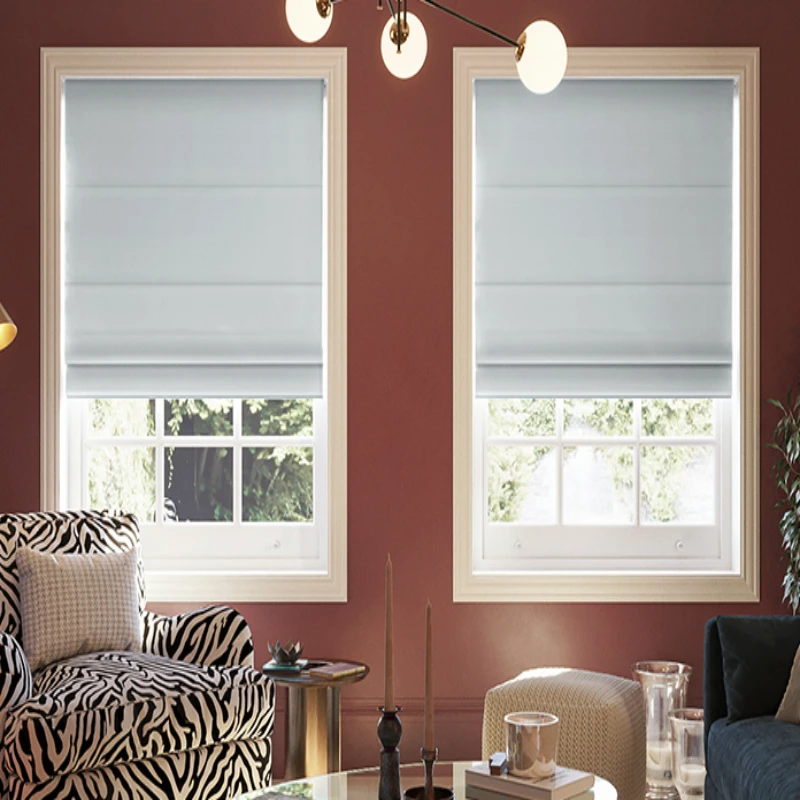 room with a red wall, a patterned armchair, and two windows covered with light gray Roman shades