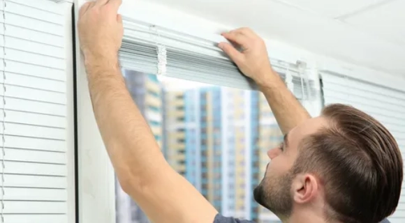 Man installing window blinds in a modern apartment