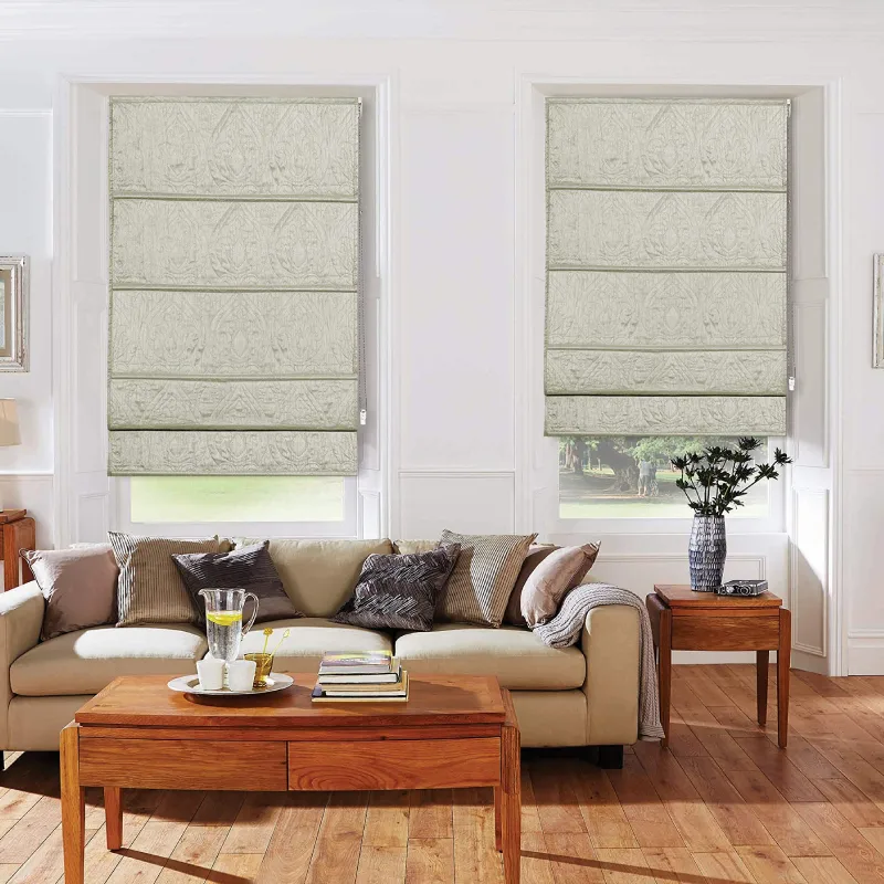 A cozy living room features a light beige sofa with throw pillows, a wooden coffee table, and two windows fitted with folded, light-colored Roman blinds.