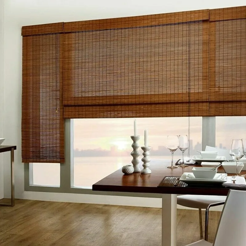 Elegant dining area with bamboo window shades and a sunset view through the window.