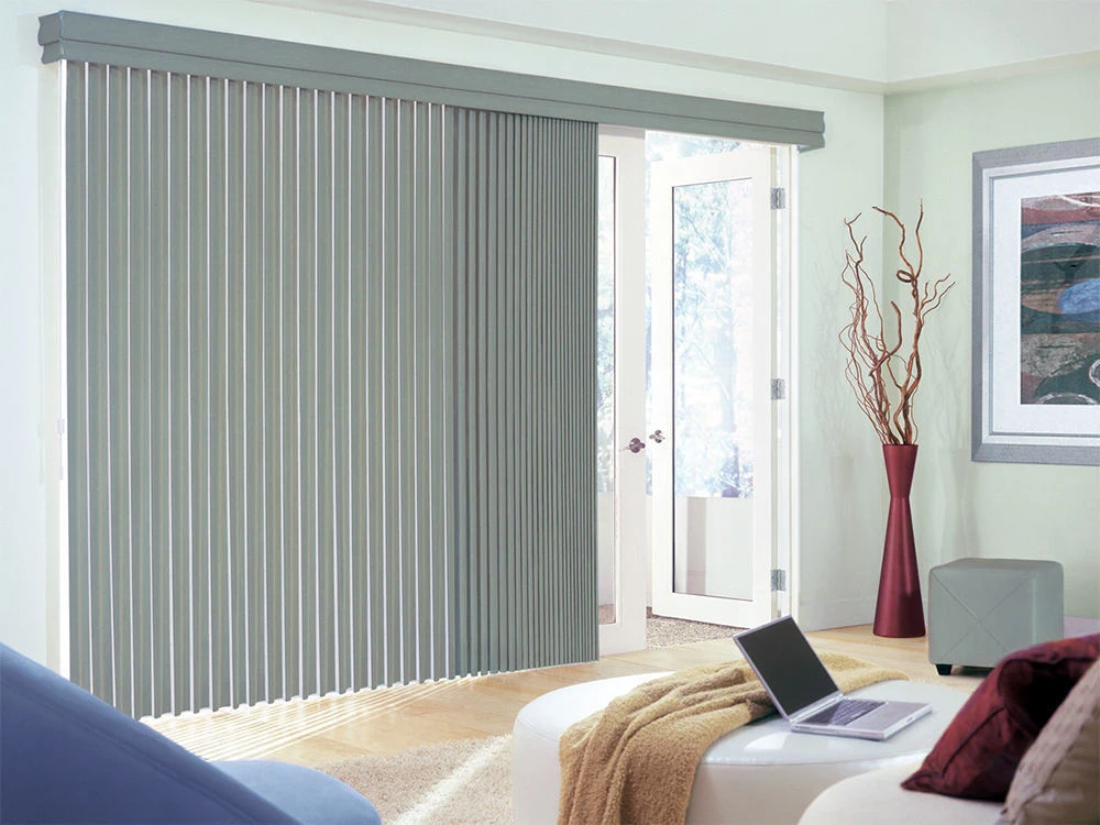 Light gray vertical blinds partially covering a sliding glass door that leads to the outside.