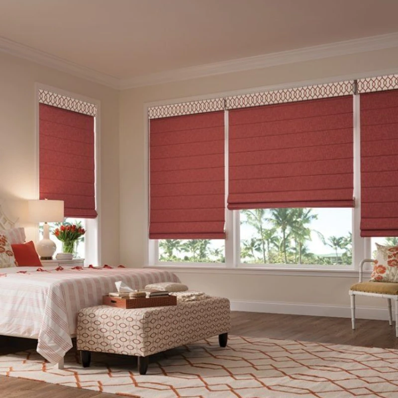 Red Roman shades with a patterned top border in a bedroom.